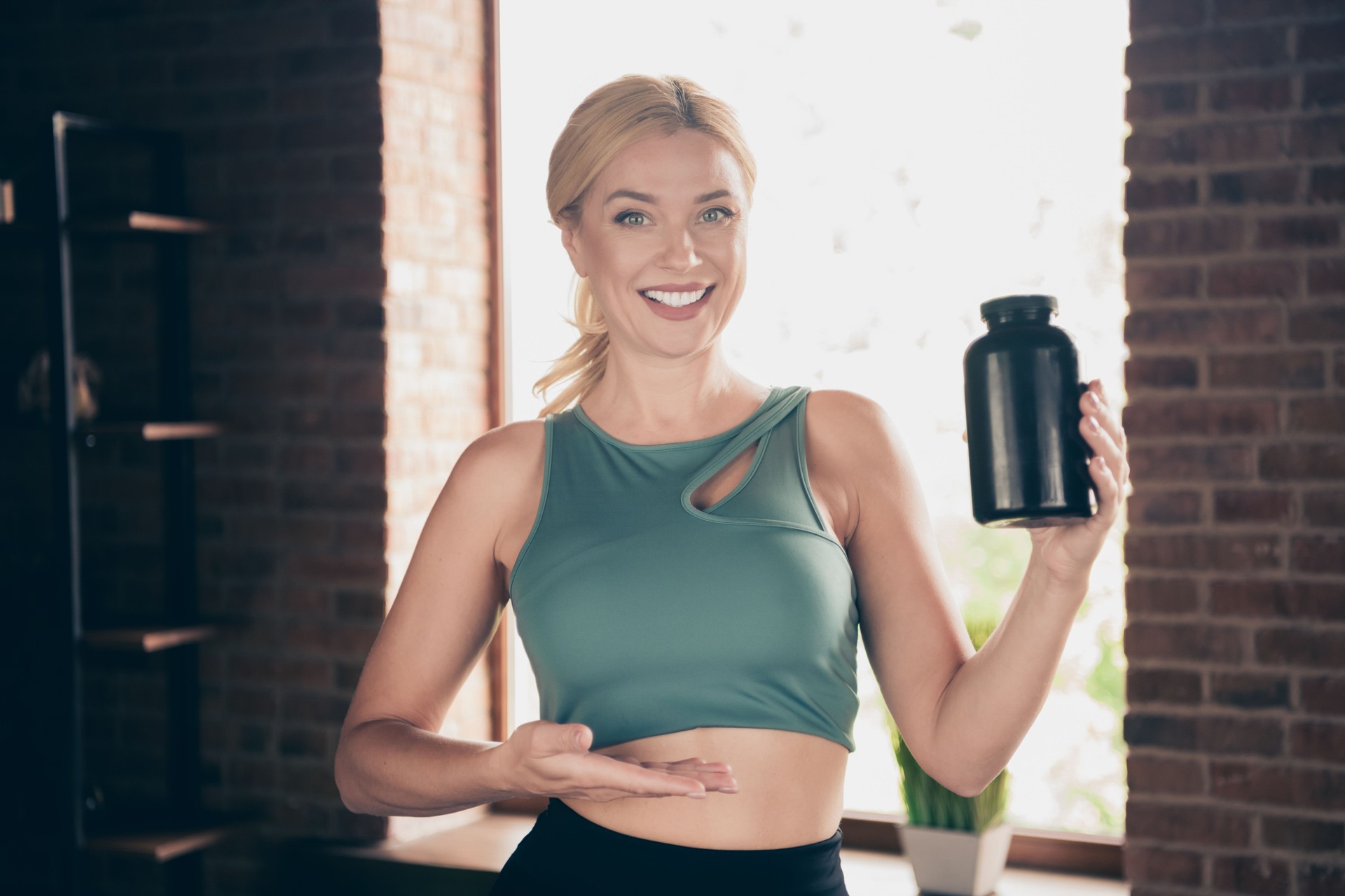 Photo of positive girl coach online blogging demonstrate protein jar recommend in house indoors